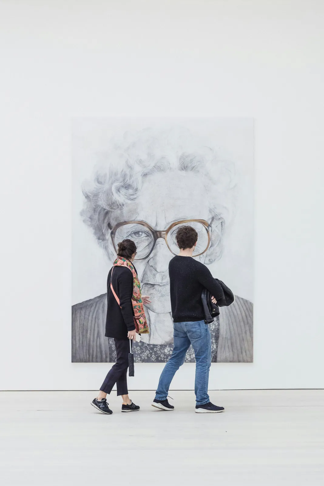 Two people looking together at a large portrait in an art gallery