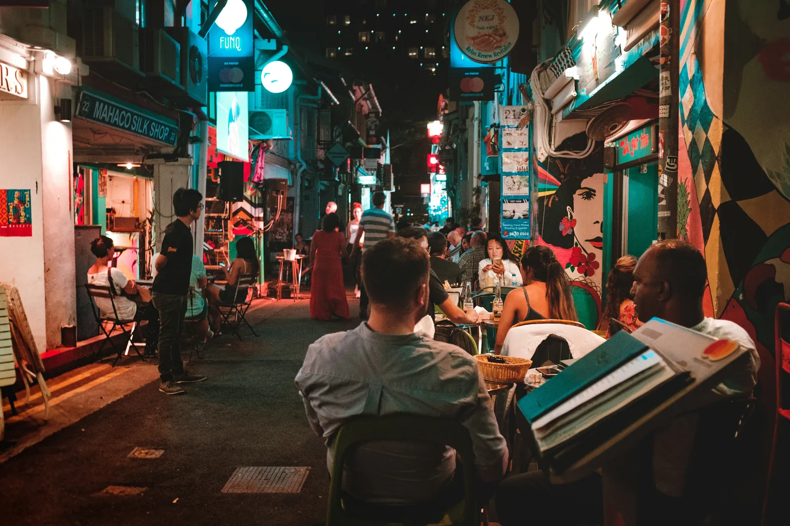 A crowd at outdoor tables in a Singapore shophouse laneway at night
